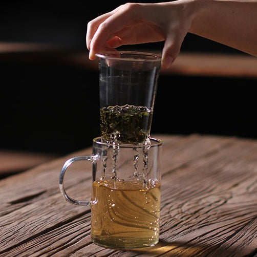Handmade glass tea mug featuring a mountain infuser, ideal for tea lovers.