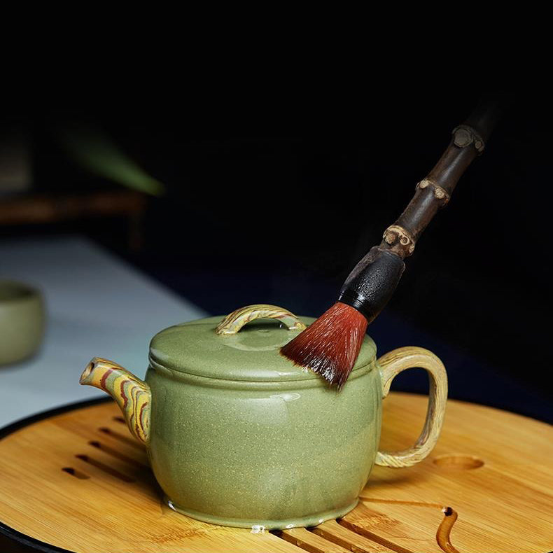 Close-up of handmade Yixing green clay teapot with smooth, rounded body and curved spout