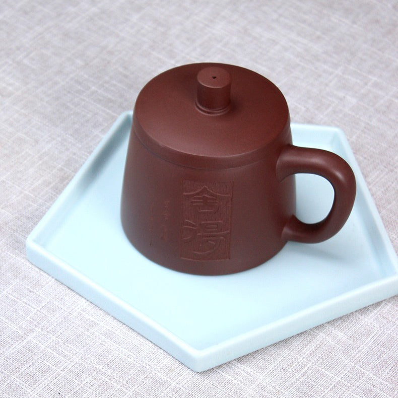 Close-up of purple clay Yixing teacup with infuser showing detailed craftsmanship