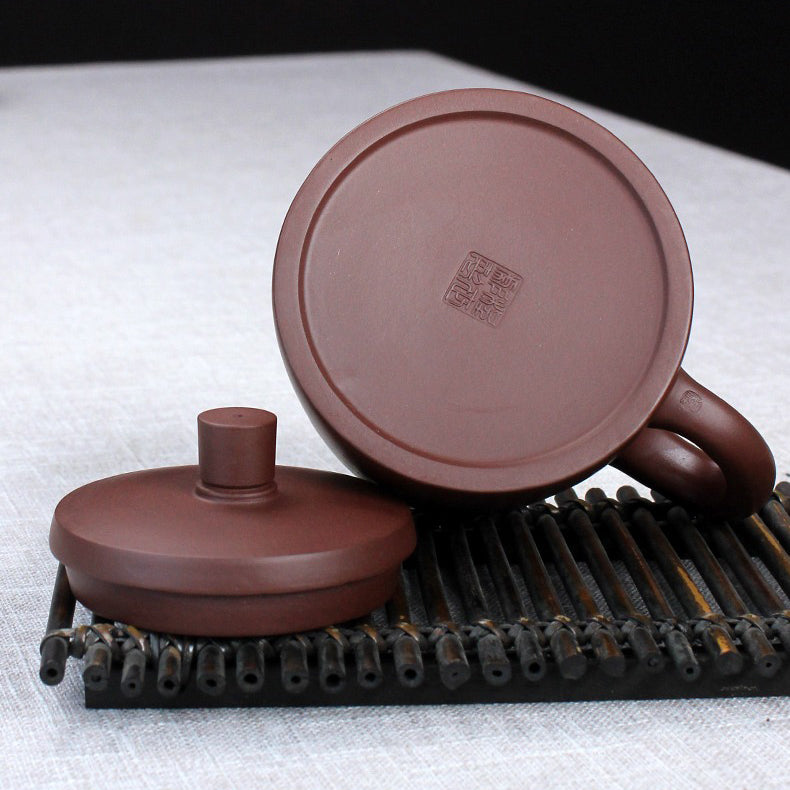 Close-up of purple clay Yixing teacup with infuser showing detailed craftsmanship
