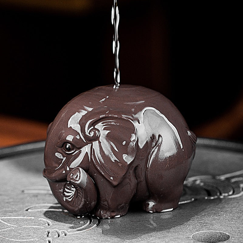 Yixing clay elephant tea pet on a tea tray with tea leaves