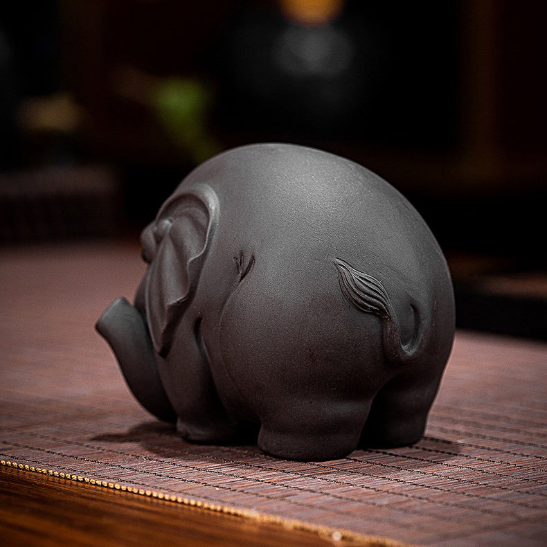 Yixing clay elephant tea pet on a tea tray with tea leaves