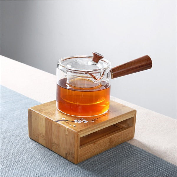 Close-up of bamboo candle teapot warmer with tea pot on top, showcasing natural bamboo finish