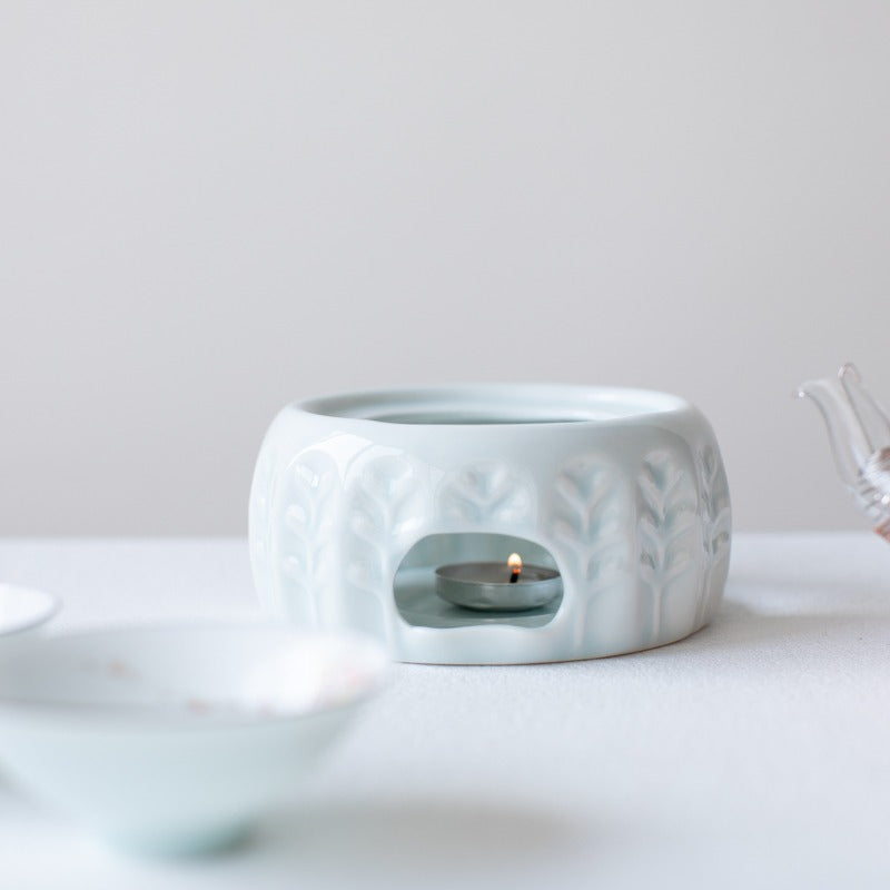 Lifestyle shot of ceramic tea warmer on a wooden tray with black tea