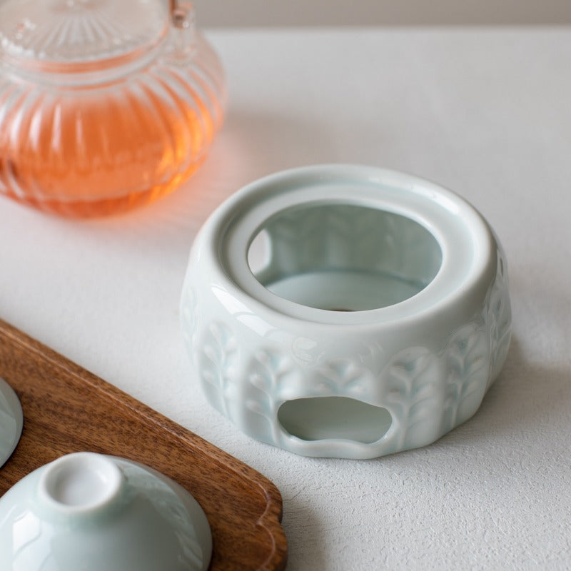 Side view of ceramic tea warmer with teapot, showing candle placement