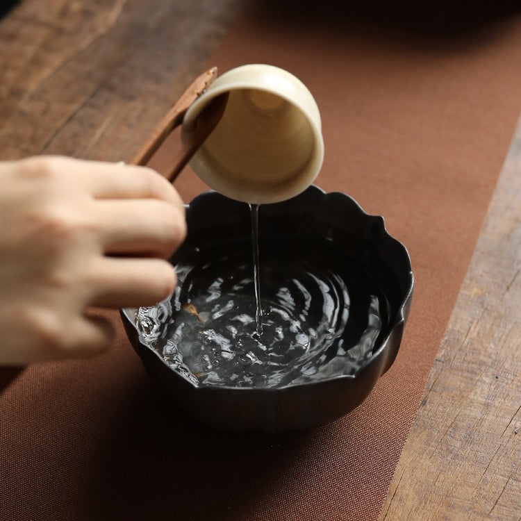 Lotus shaped ceramic tea washer in use during a traditional tea ceremony.