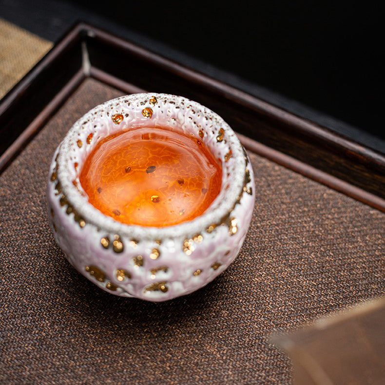 Close-up view of the pink glazed tea cup, highlighting the flowing-gold glaze and retro style.