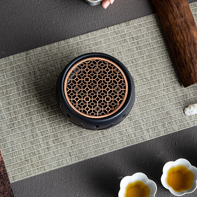 Tea being poured from a teapot onto the ceramic warmer with lotus design