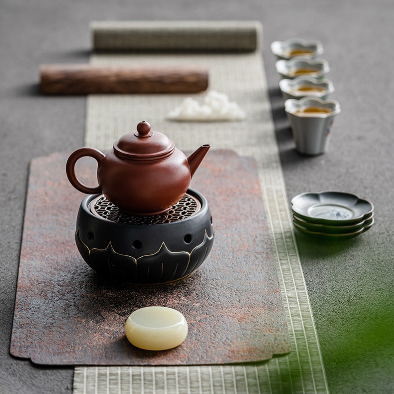 Stylish black ceramic teapot warmer with a lit tealight underneath