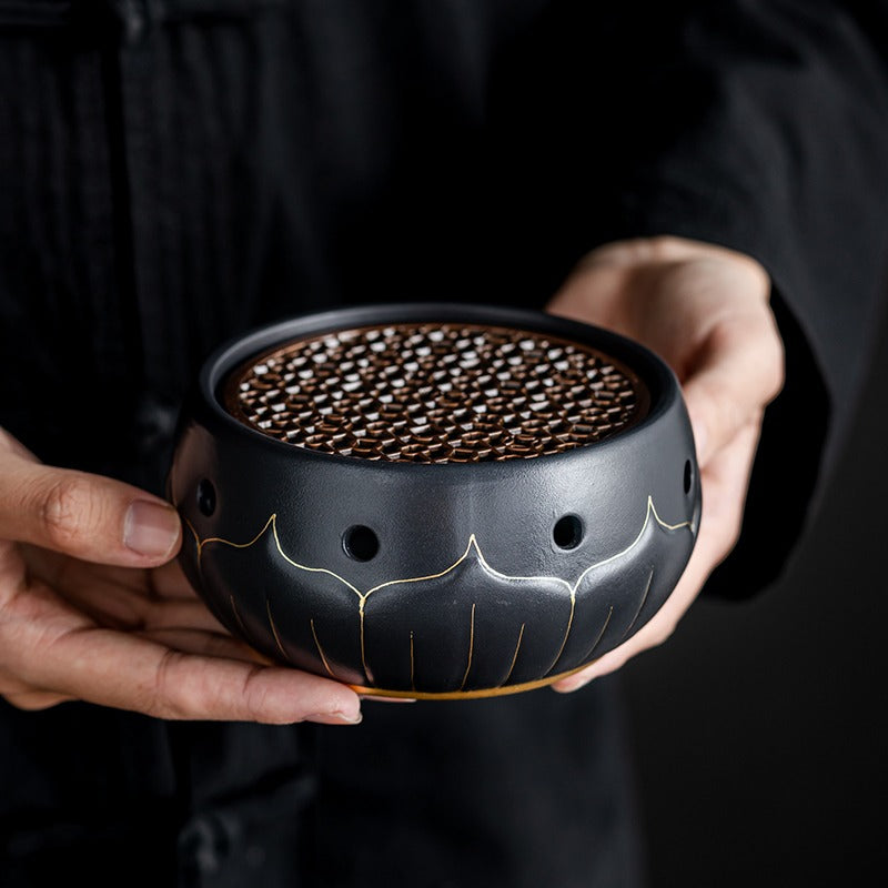 Stylish black ceramic teapot warmer with a lit tealight underneath