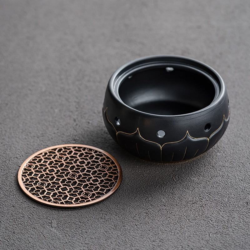 Close-up of black ceramic lotus teapot warmer with gold accents