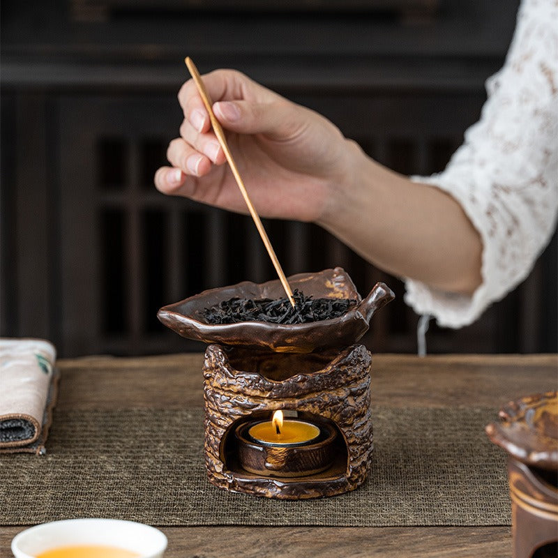 Side view of the tree stump tea warmer, highlighting the hand-polished base and leaf-shaped saucer.