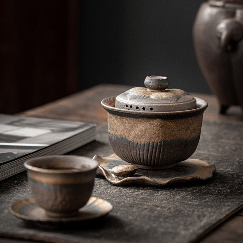 Side angle of coarse pottery teapot with lotus leaf base and downward spout