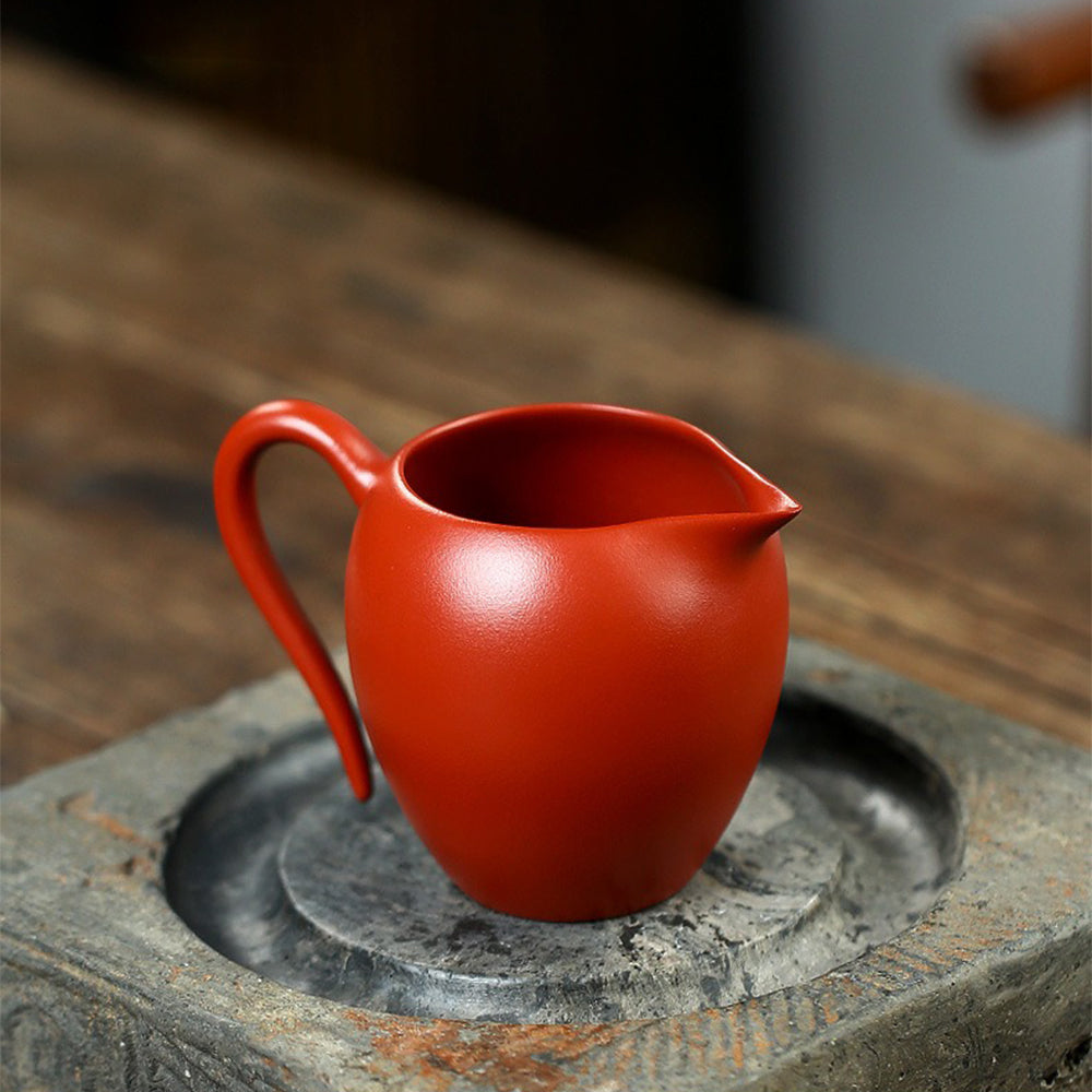 Lotus-embossed Yixing red clay fair cup from a side angle, showcasing its elegant design.