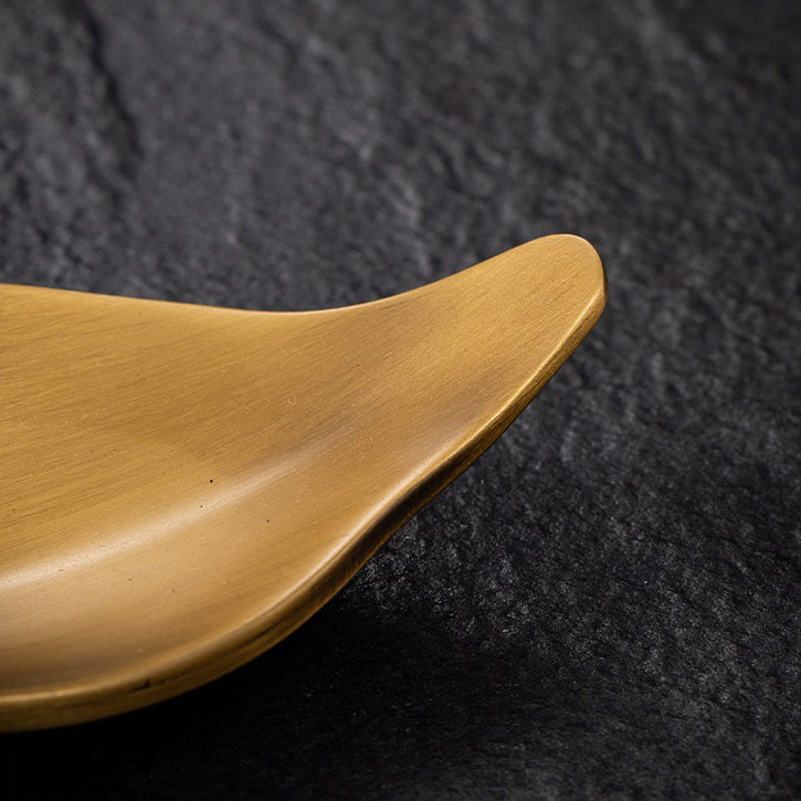 Lotus spoon placed beside the brass tea holder, designed for elegant tea serving.