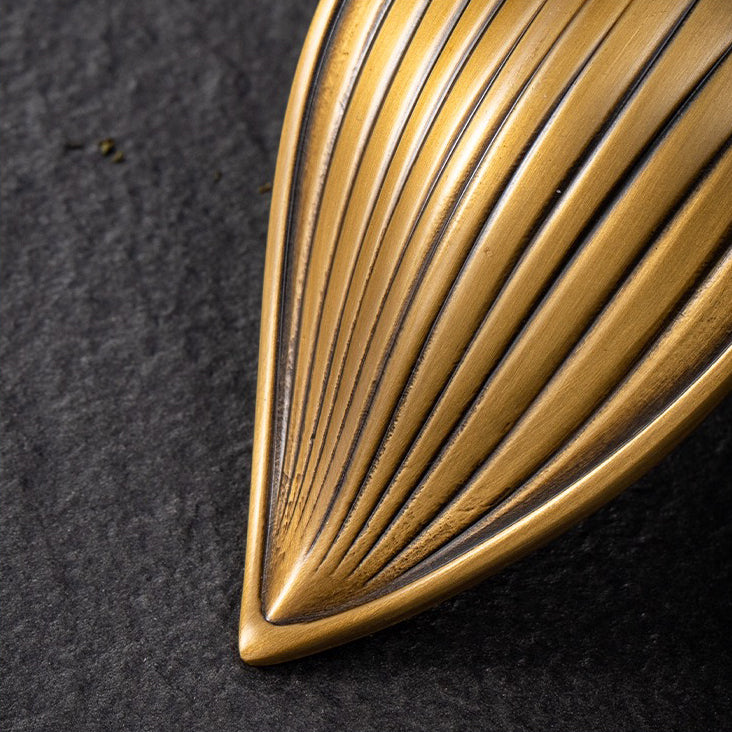 Artisan brass tea holder showcasing dry tea leaves during a tea ceremony.