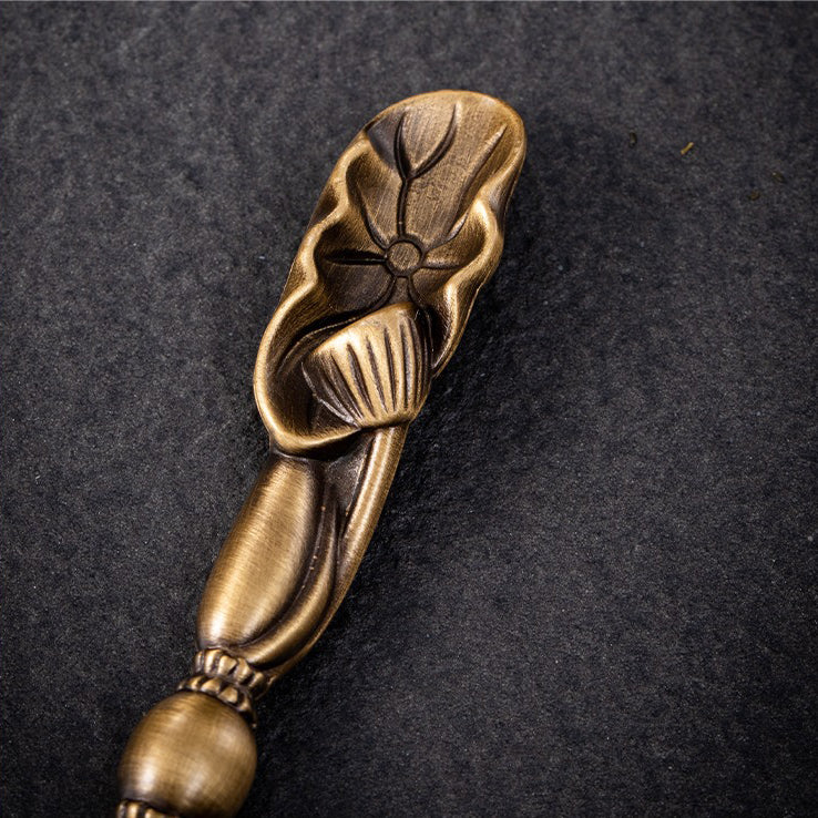 Lotus spoon placed beside the brass tea holder, designed for elegant tea serving.