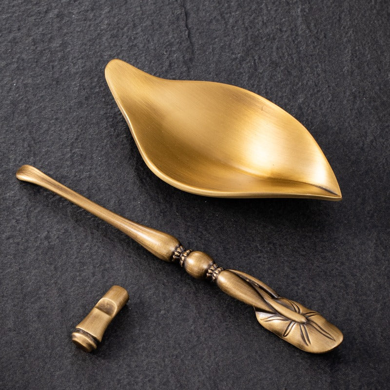 Lotus spoon placed beside the brass tea holder, designed for elegant tea serving.
