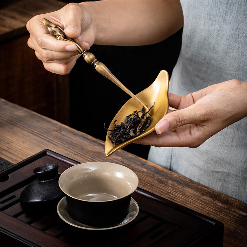 Lotus spoon placed beside the brass tea holder, designed for elegant tea serving.
