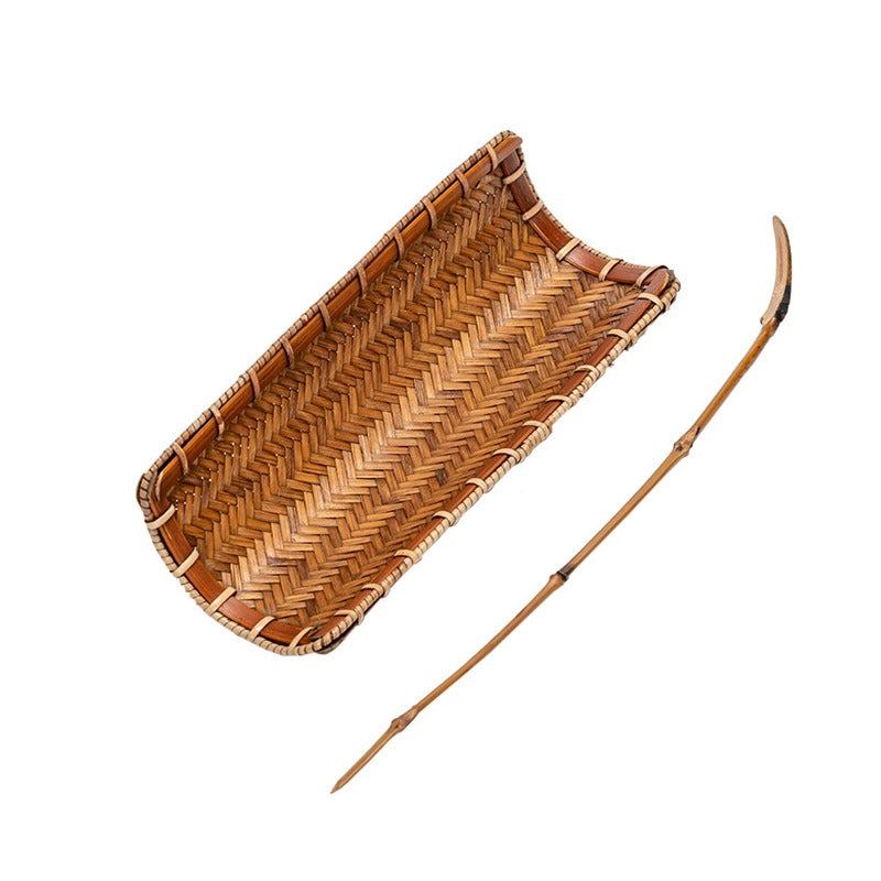 Elegant bamboo tea holder with spoon displayed with dry tea leaves in a cozy setting.
