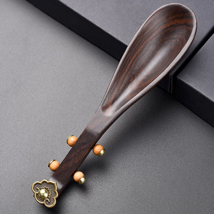 Tea host presenting dry tea leaves with an ebony tea holder