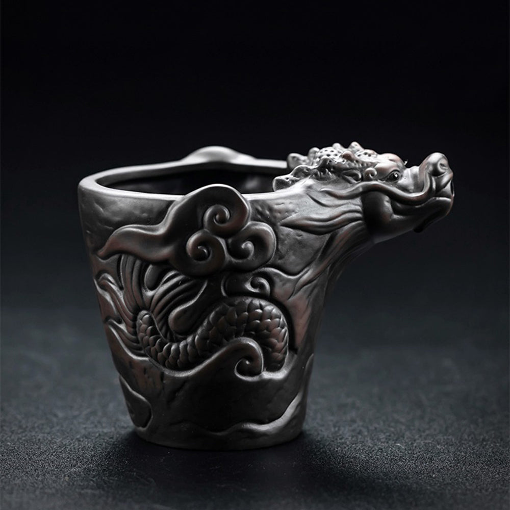 A close-up of the dragon-carved Yixing teapot resting beside the fair cup on a bamboo tray, showcasing steam rising from fresh pu-erh tea.