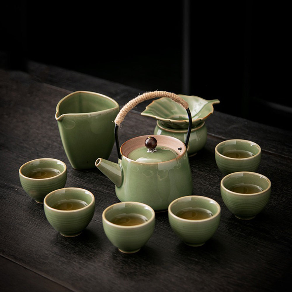 Elegant Japanese celadon tea set with teapot and cups displayed on a wooden table.