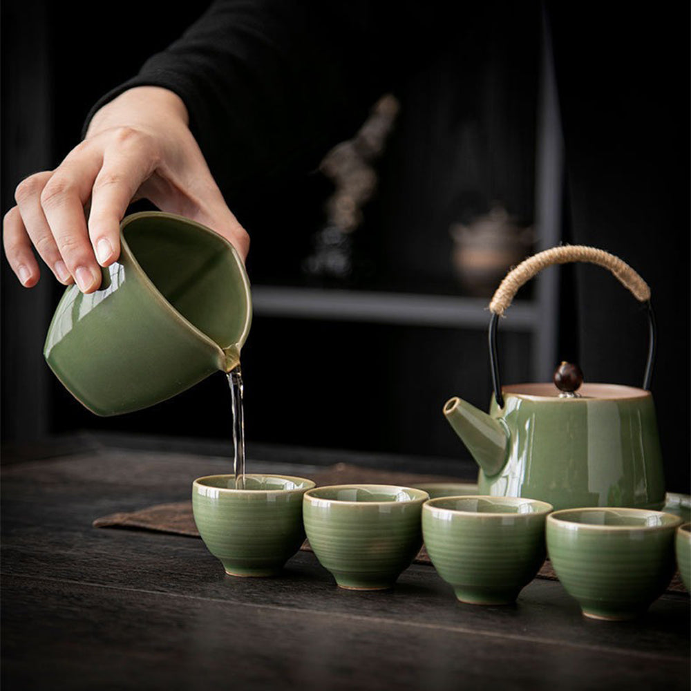 Elegant Japanese celadon tea set with teapot and cups displayed on a wooden table.