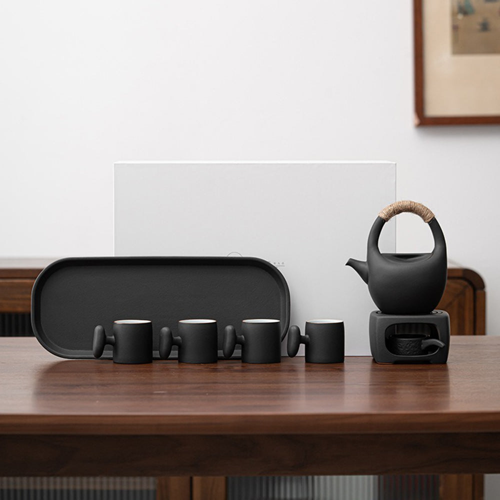 Elegant Japanese black pottery tea set with warmer displayed elegantly on a table.