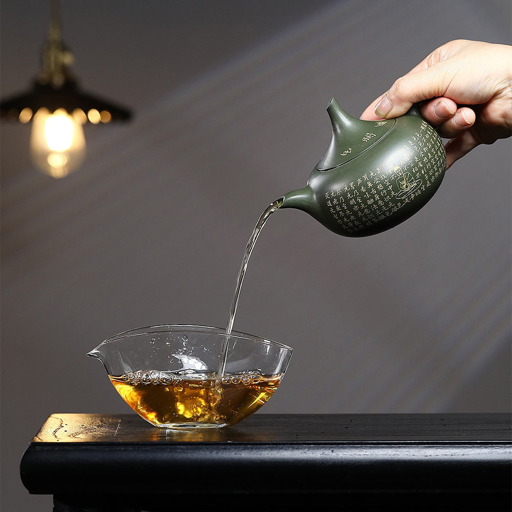 Yixing green clay teapot pouring tea with a smooth spout and ergonomic handle