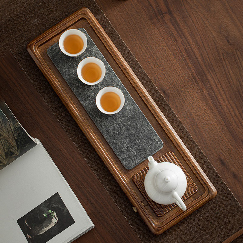Elegant black stone tea tray with bamboo accents, showcasing its drainage feature.