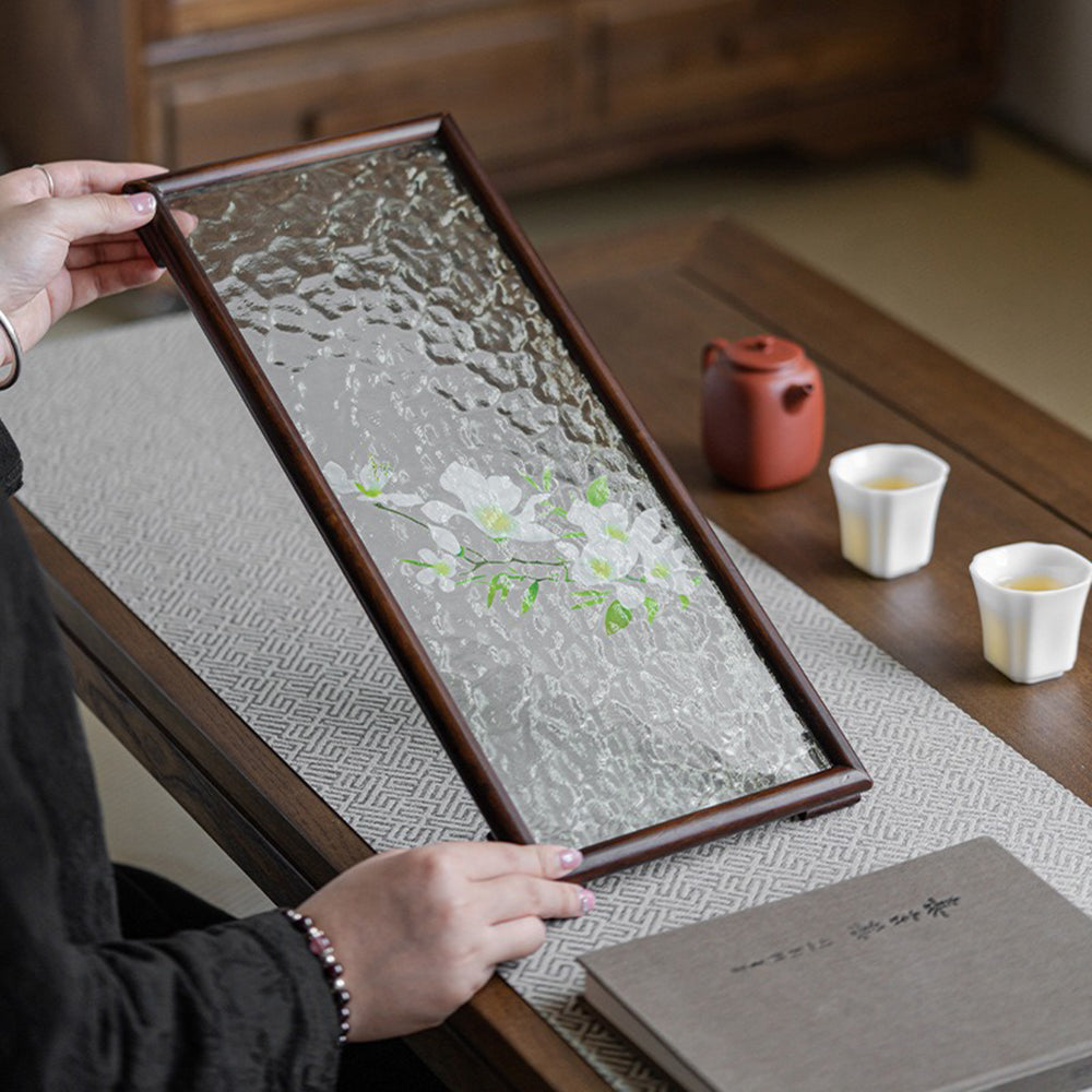 Close-up of water ripple glass surface with floral design on walnut tea tray