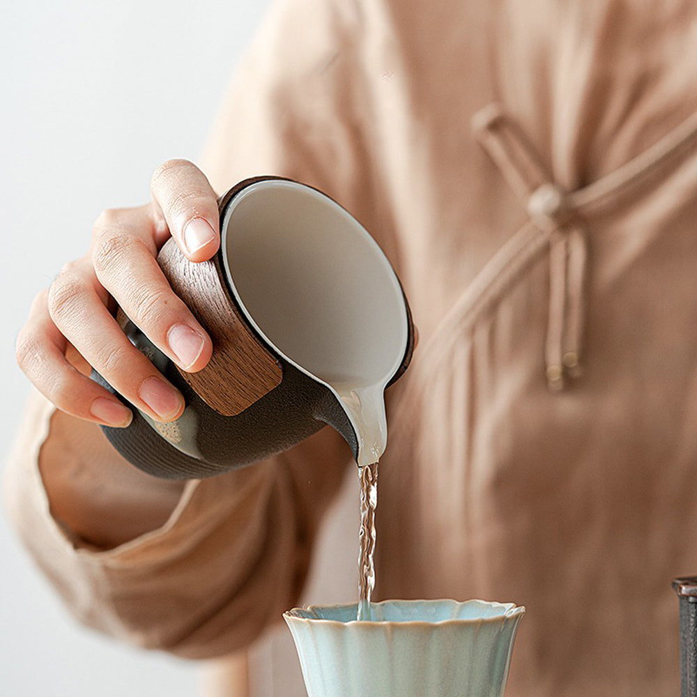 Side view of black pottery tea strainer set showing walnut-wrapped fair cup and maple leaf detailing