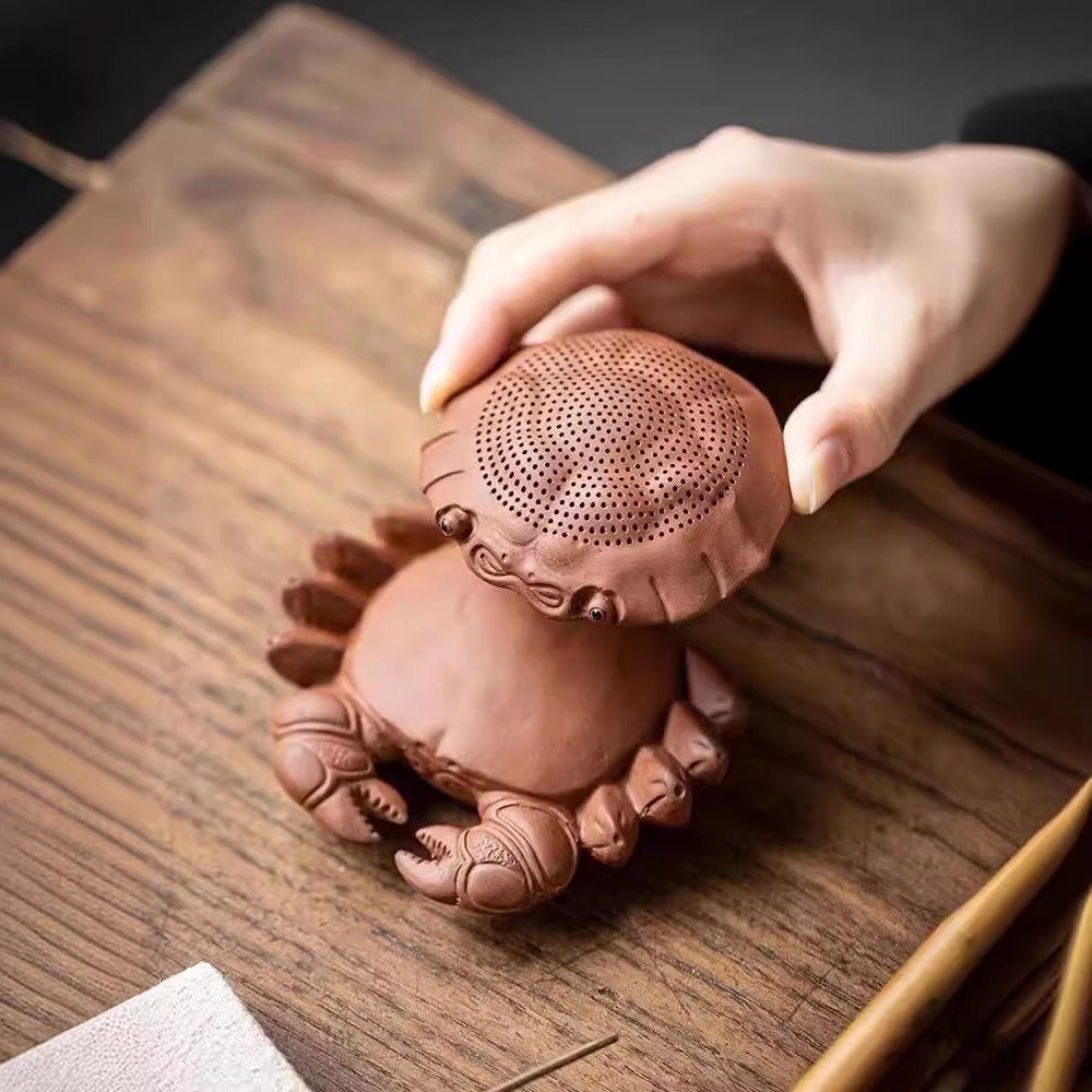Close-up of a purple clay crab tea pet with bright eyes and detailed shell, used as a tea accessory and home decor