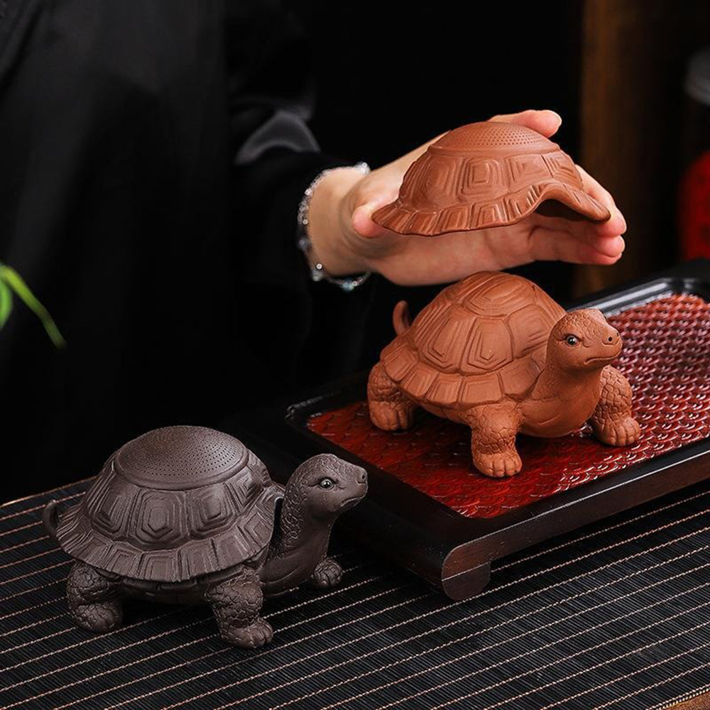 Purple clay turtle tea strainer on a tea table, showcasing its dual function.