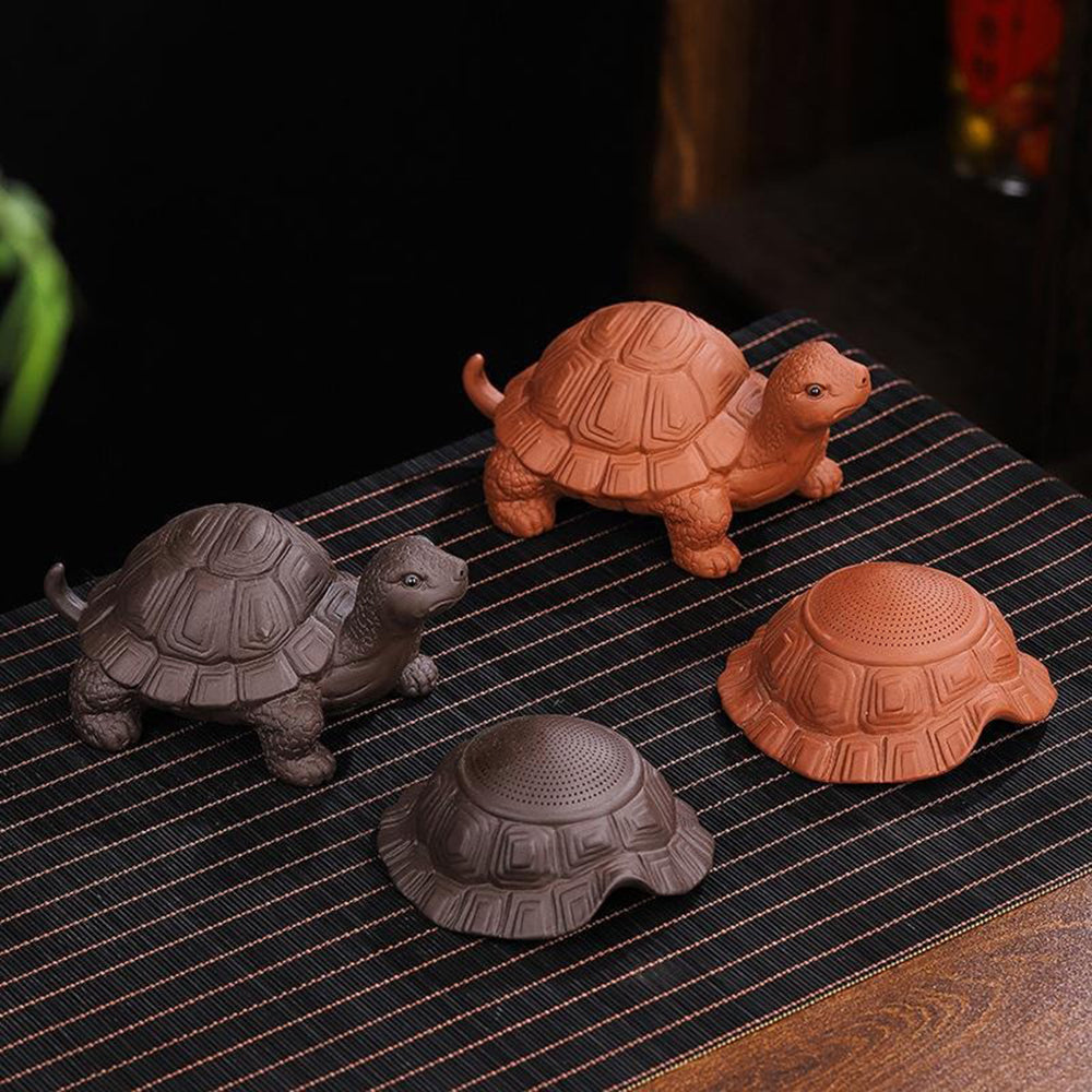Purple clay turtle tea strainer on a tea table, showcasing its dual function.