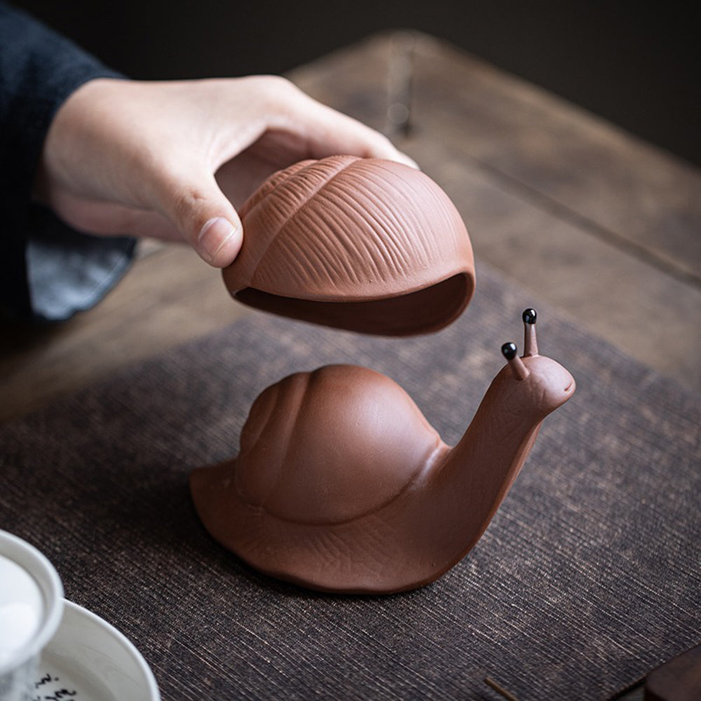 Purple clay snail tea pet with intricate details, used as a tea strainer and decor