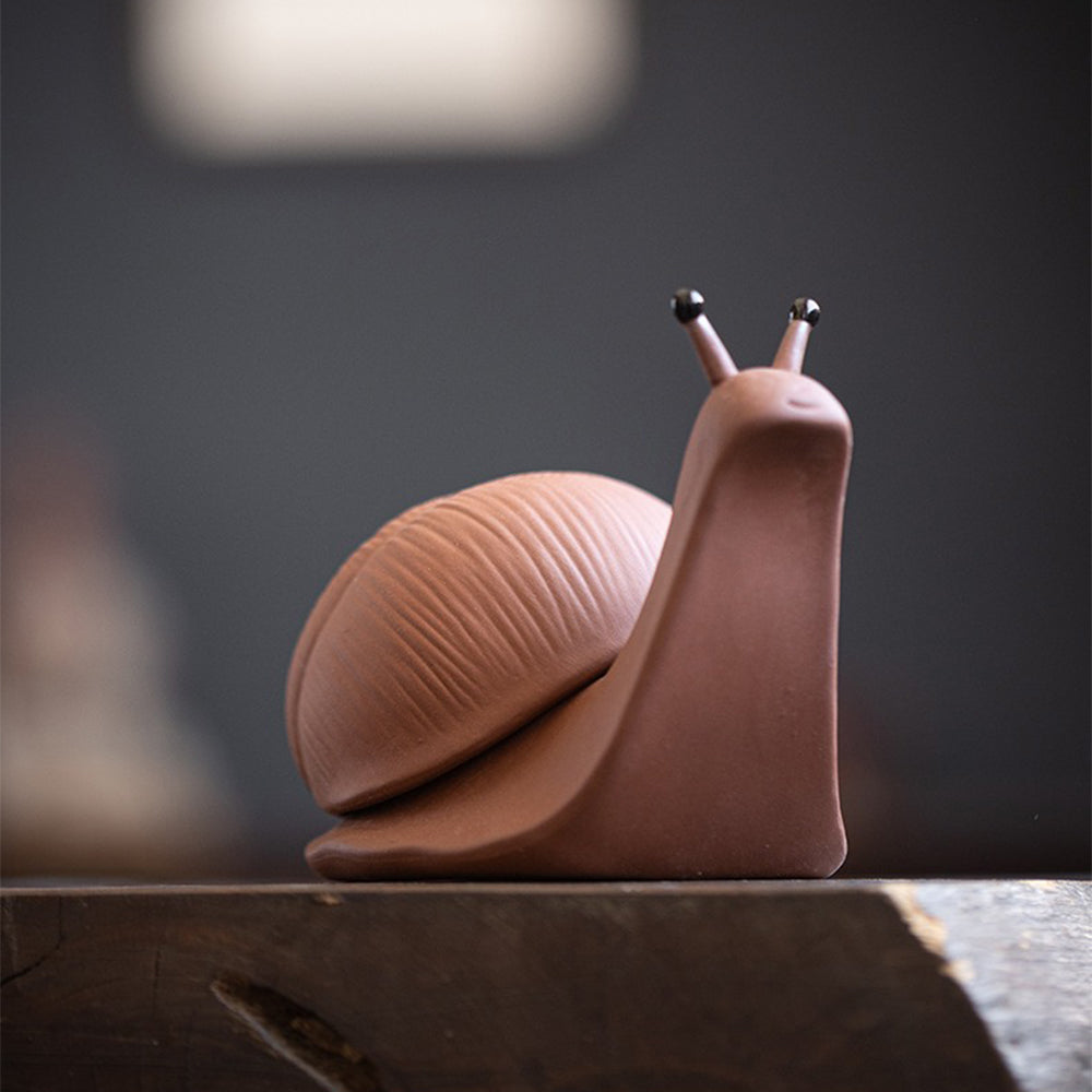 Tea pet and strainer set with the snail holding a tea leaf brew, showcasing its cute design