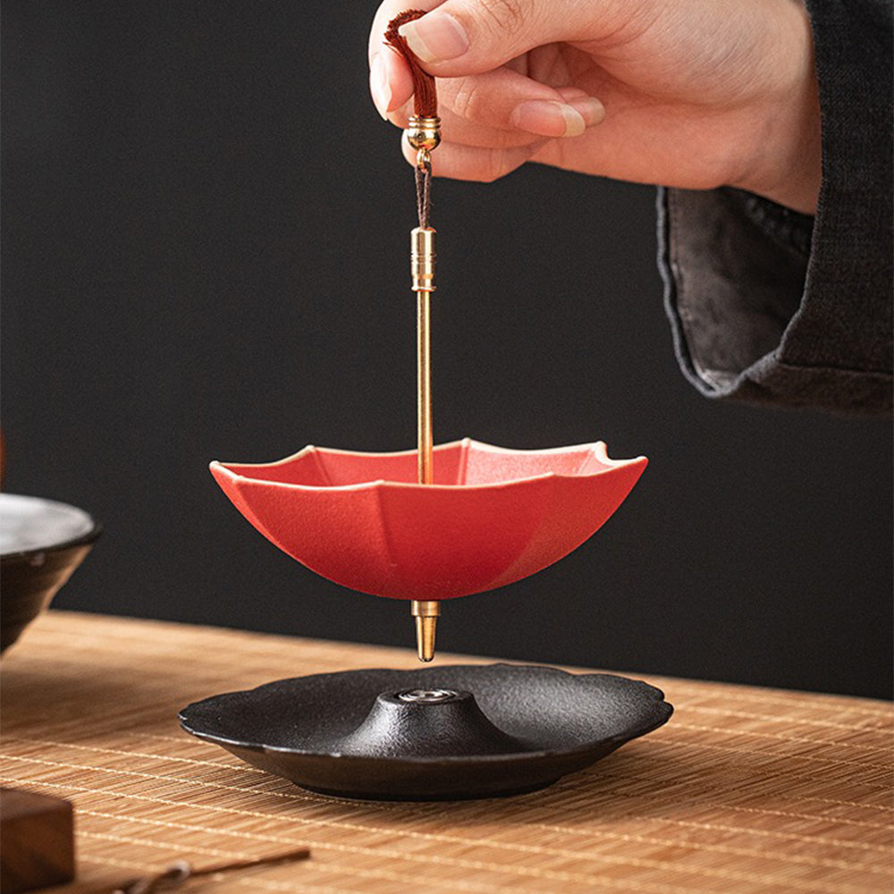 Charming ceramic umbrella tea strainer on a tea cup, showcasing its unique design.
