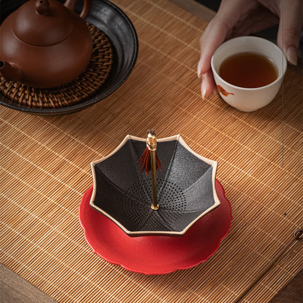 Close-up of the ceramic umbrella tea strainer with loose tea leaves, highlighting its filter holes.