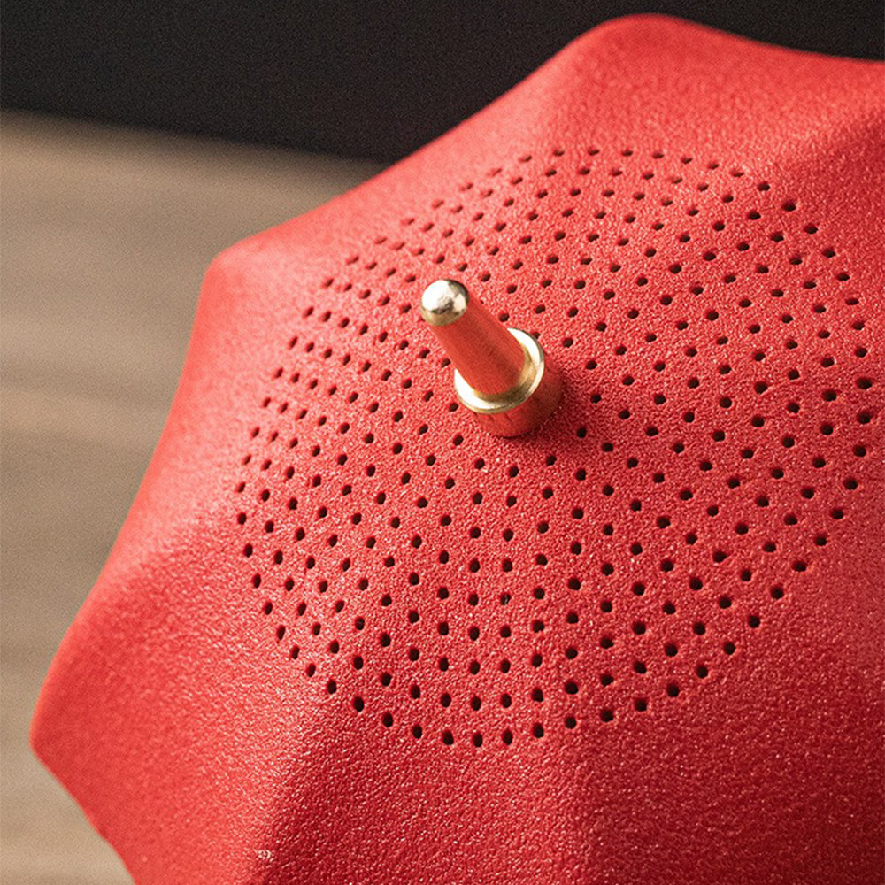 Ceramic umbrella tea strainer placed on its holder, adding a decorative touch to a tea table.