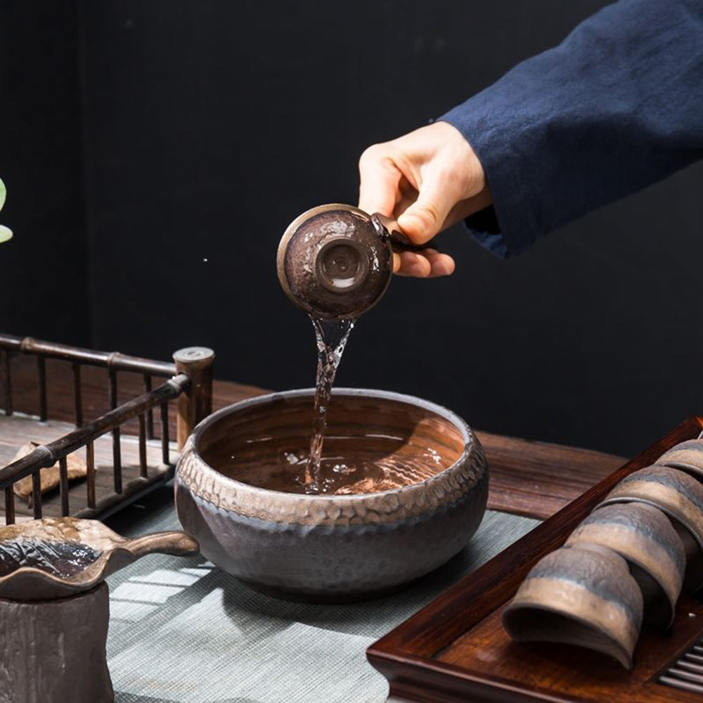 Elegant pottery tea set with teapot, cups, and strainer on a wooden table