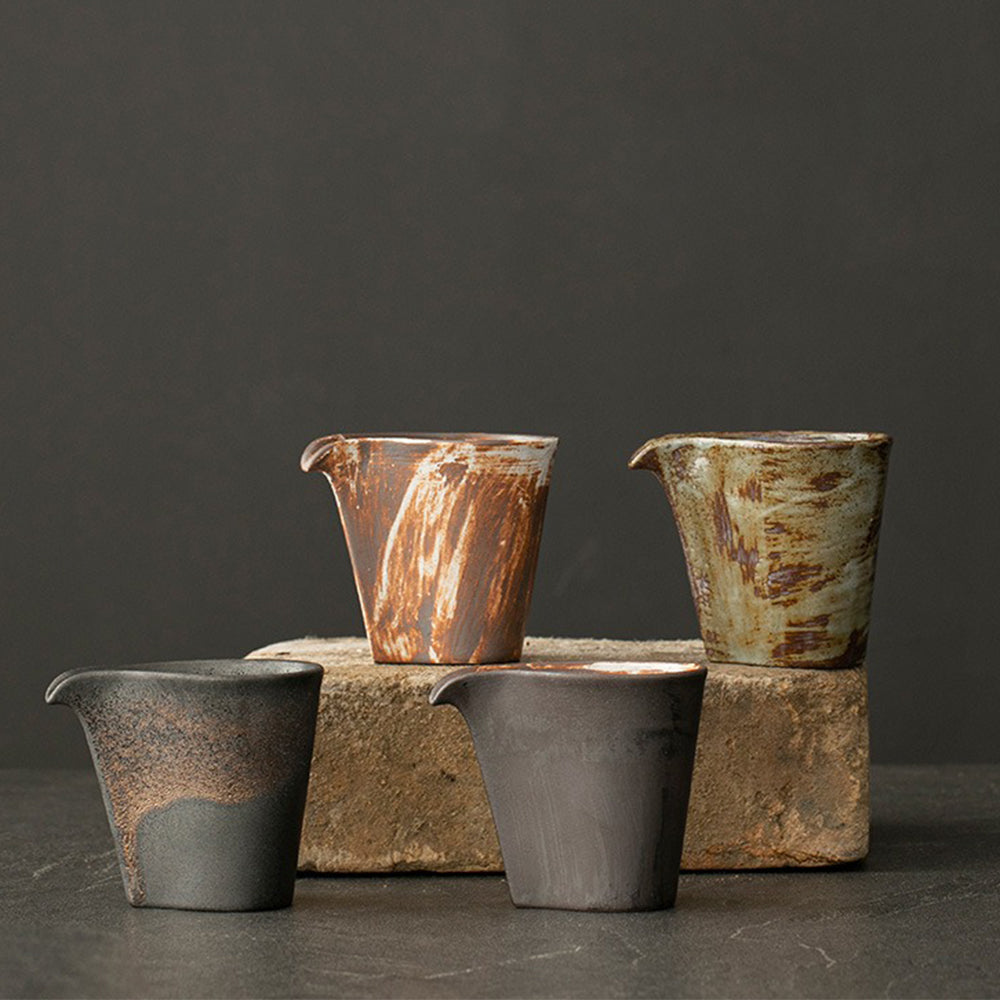 Handmade vintage coarse pottery Japanese fair cup showing textured surface and curved spout