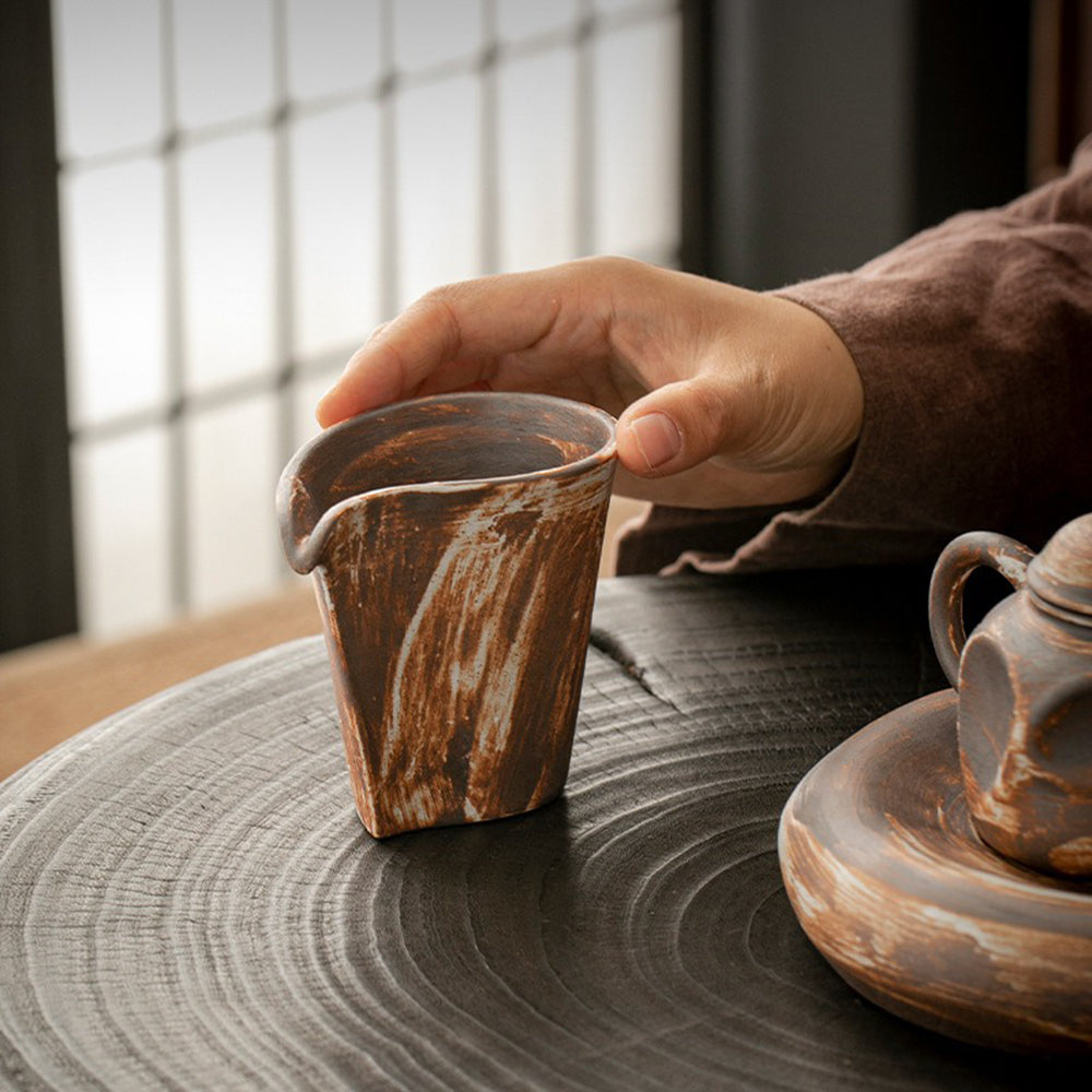 Handmade vintage coarse pottery Japanese fair cup showing textured surface and curved spout
