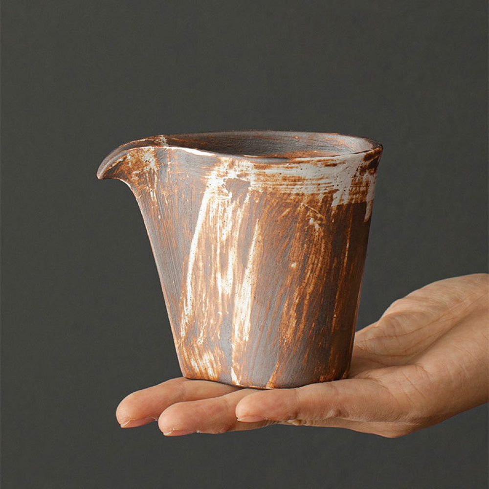 Handmade vintage coarse pottery Japanese fair cup showing textured surface and curved spout