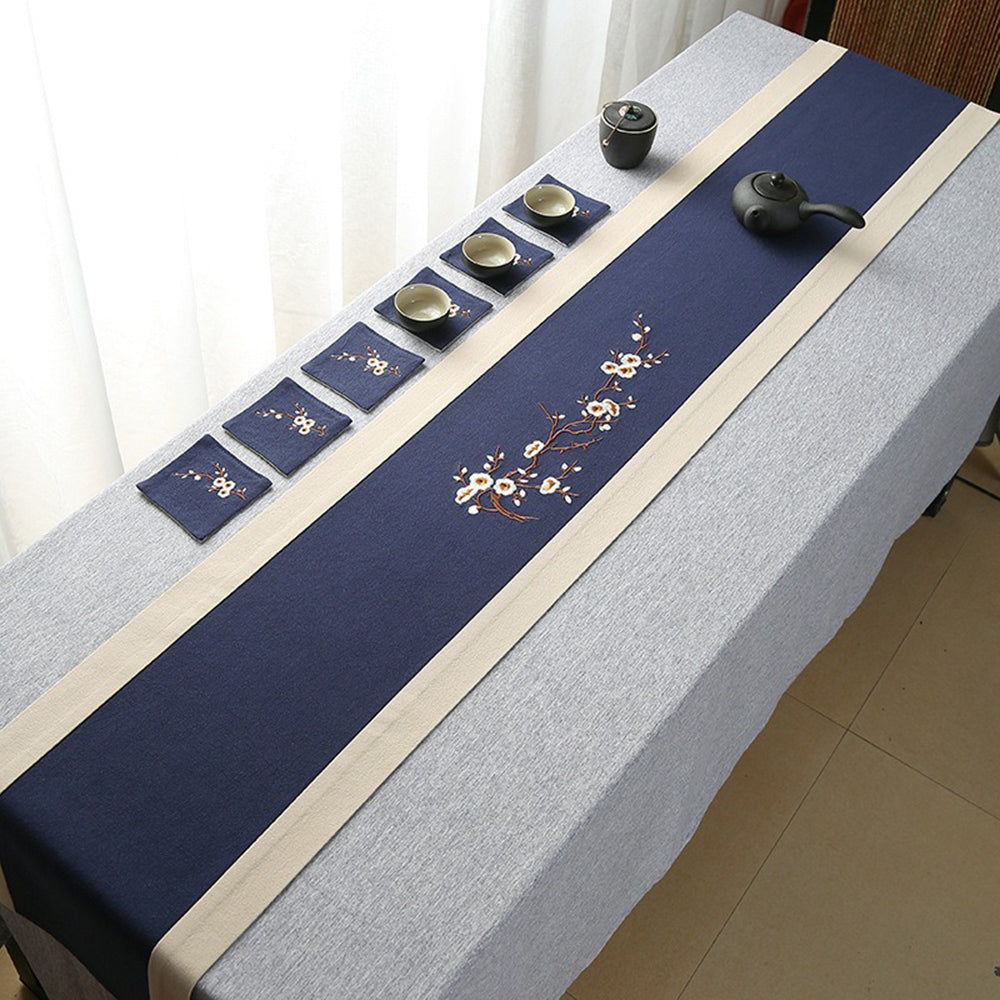Close-up of embroidered plum blossom cotton linen tea mat on a traditional tea table