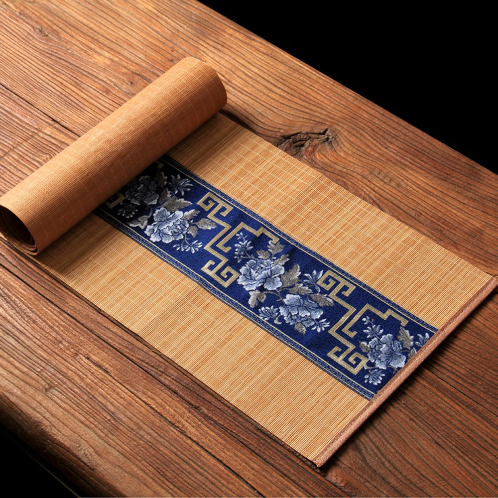 Bamboo tea mat with floral embroidery used as a tea table protector during a traditional tea ceremony