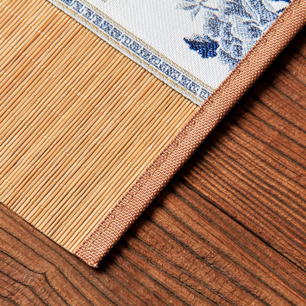 Elegant bamboo tea mat with floral embroidery, set on a table with tea utensils for a festive party