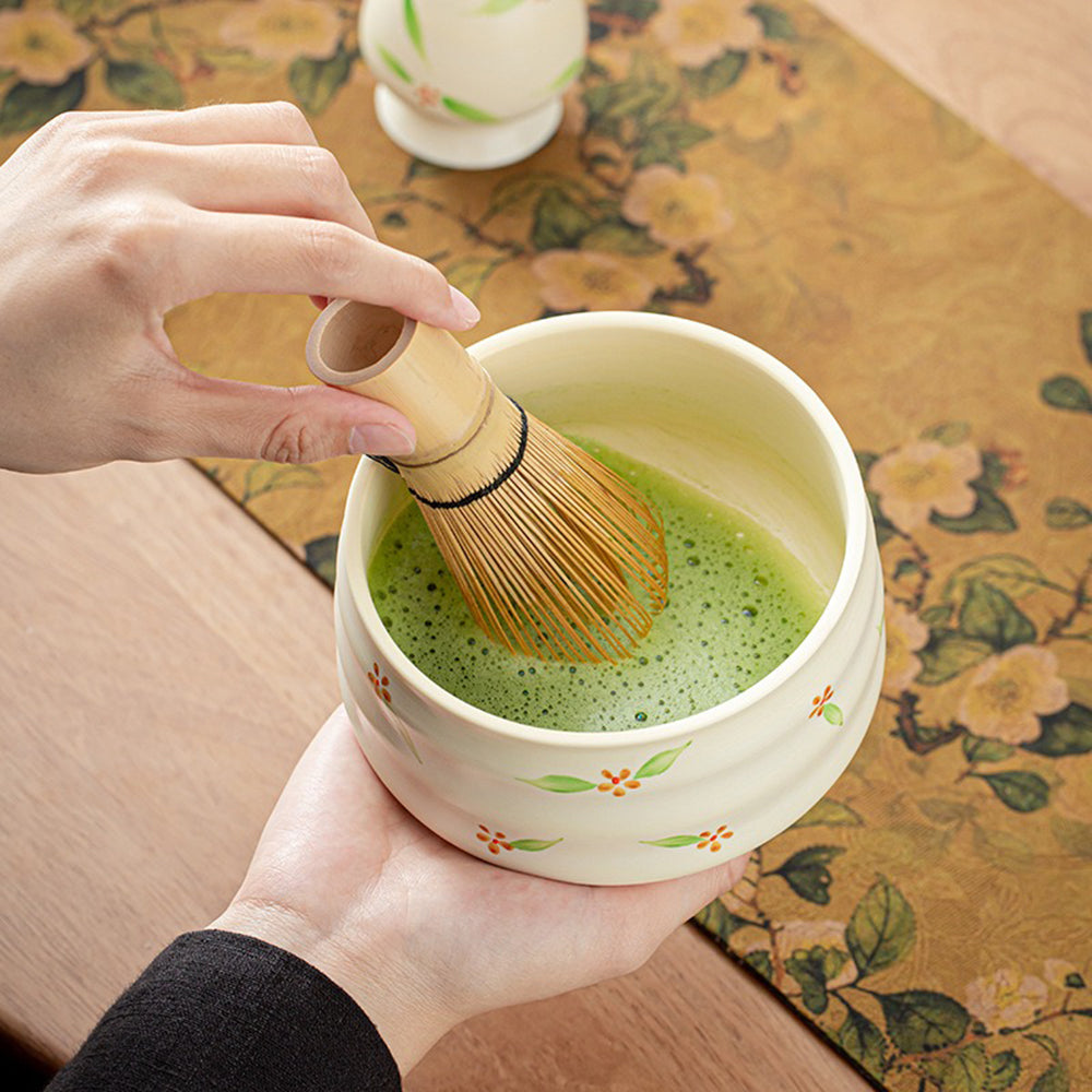 Bamboo whisk in action, stirring matcha in the ceramic bowl.