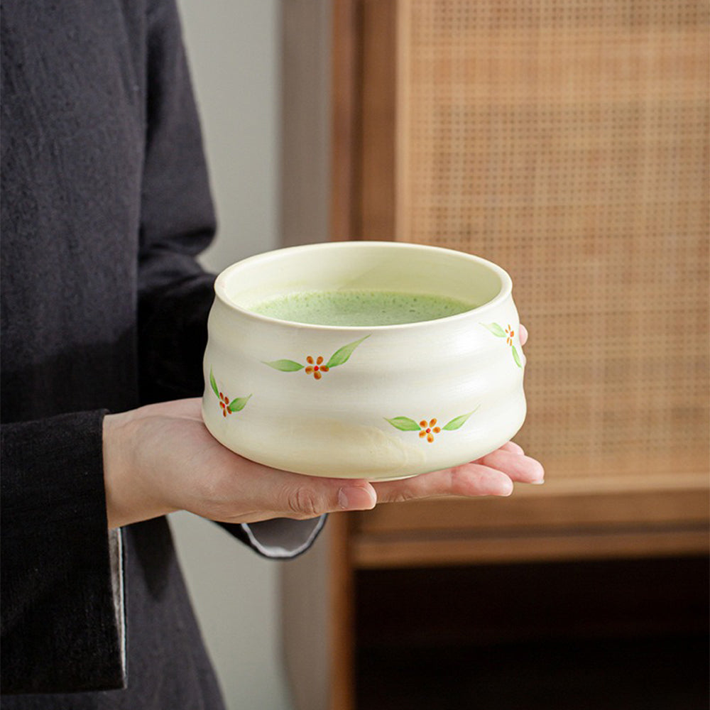 Bamboo whisk in action, stirring matcha in the ceramic bowl.